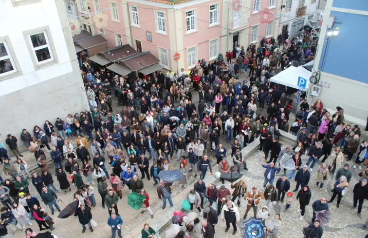Dezenas de pessoas no Bairro da Beira-mar em Aveiro a apanhar cavacas que são lançadas do topo da capela.